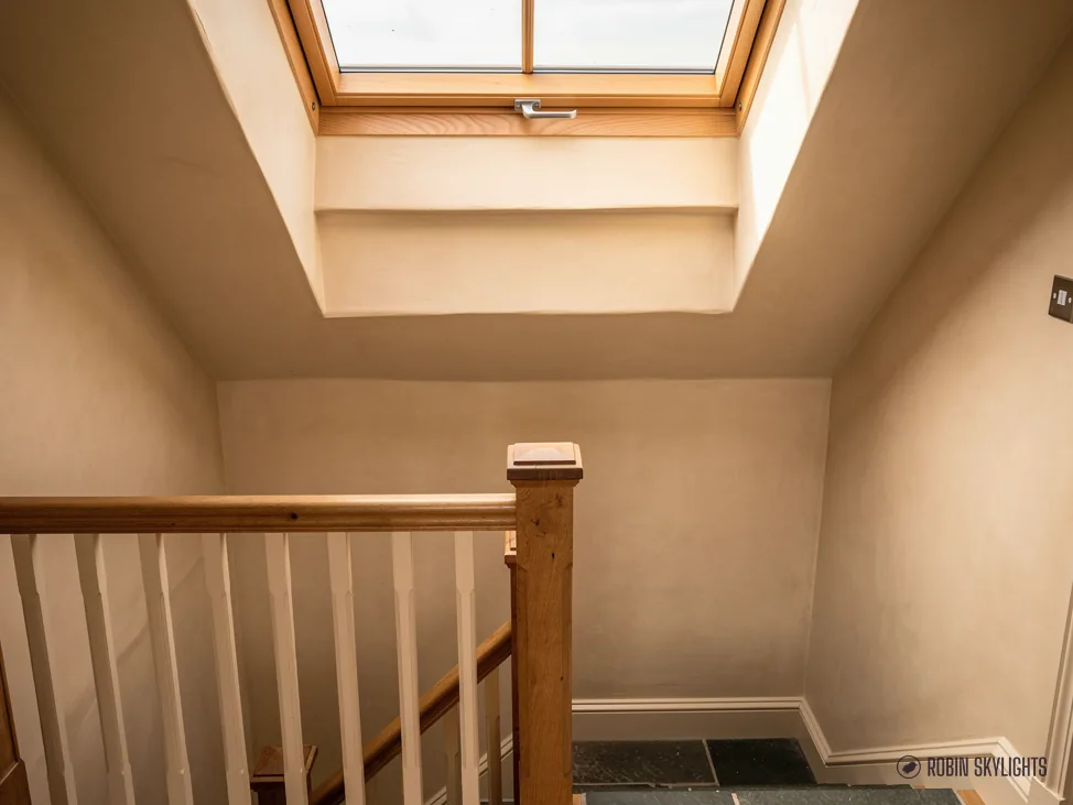 Landing with a timber banister lit by a roof window in a sloping ceiling