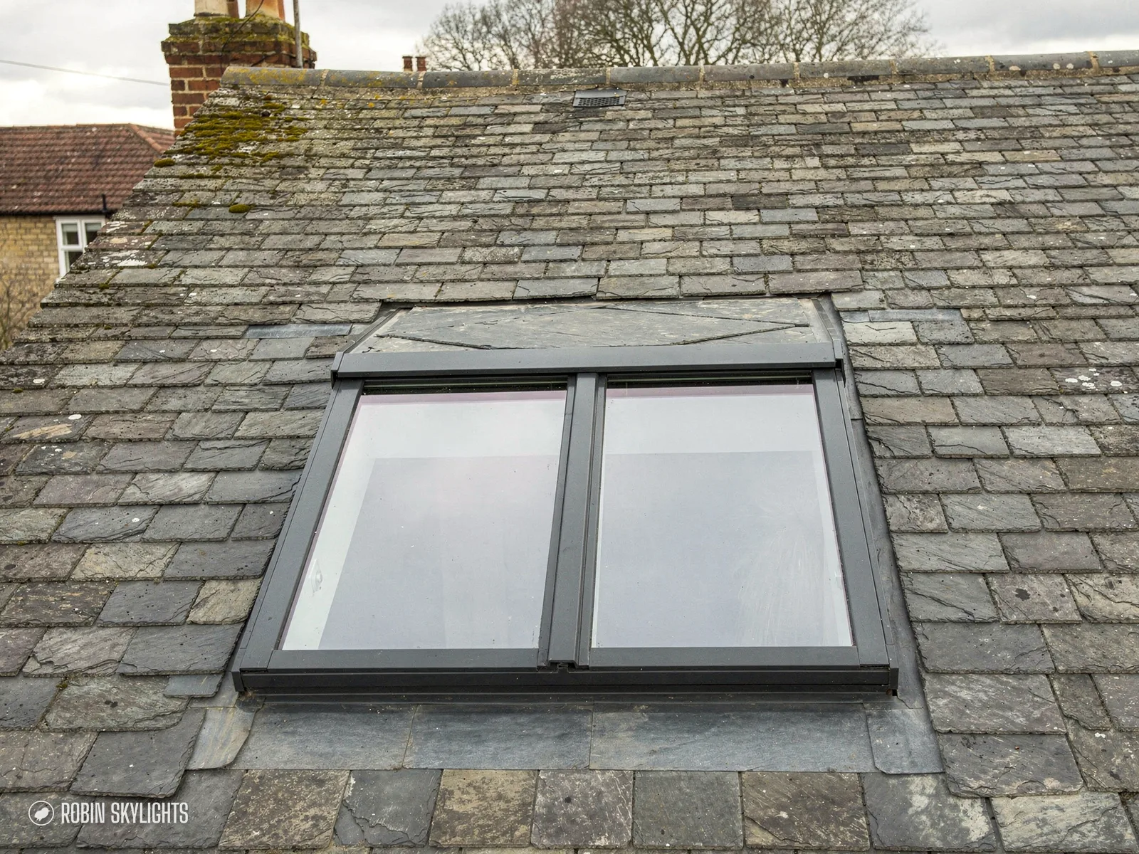 Dark framed conservation rooflight with a centre bar set low in a slate roof