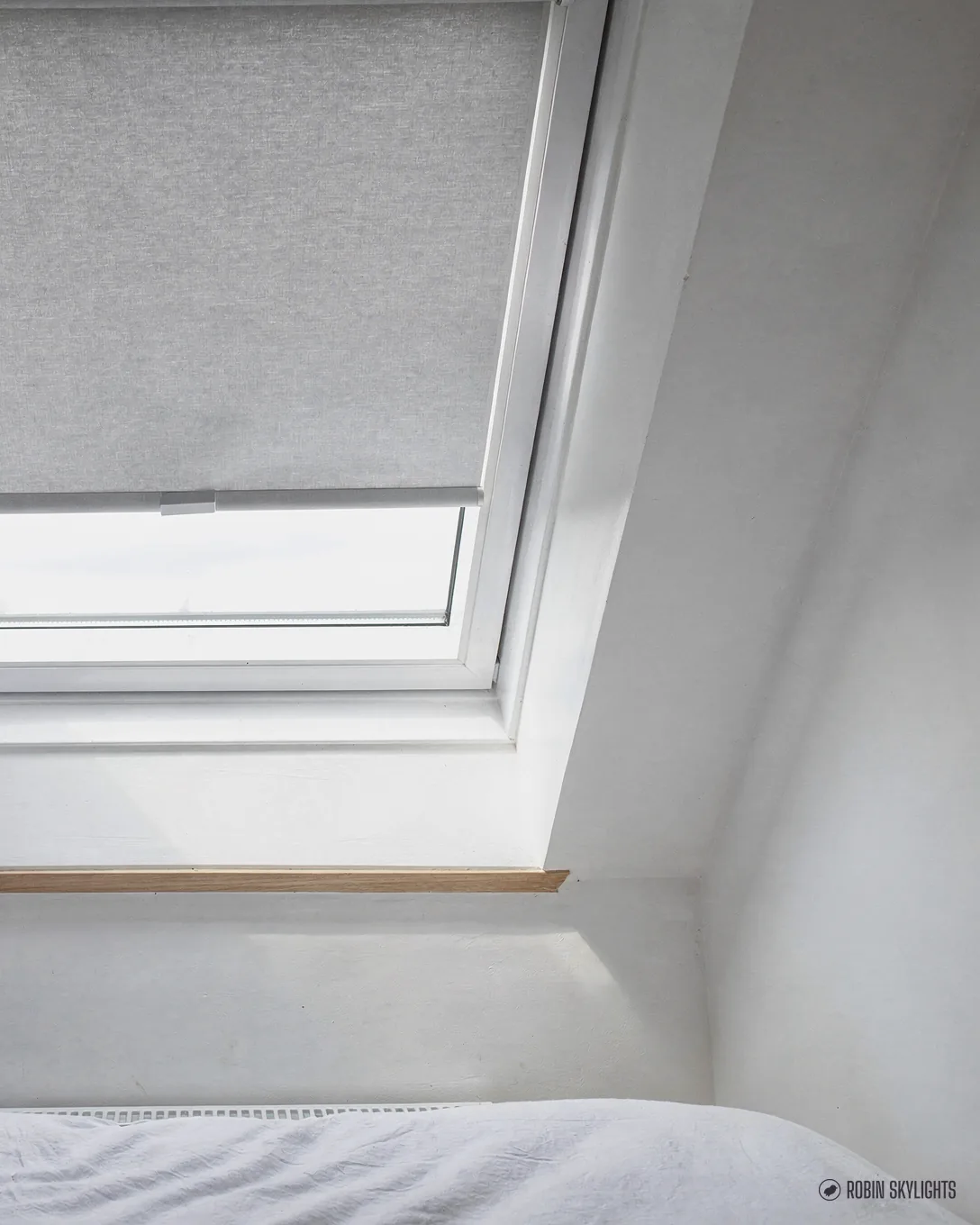 Close view of a white roof window with a pale fabric blind fitted