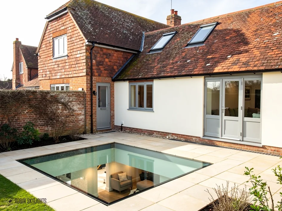 Walk-on rooflight in a stone patio beside a cottage with French doors