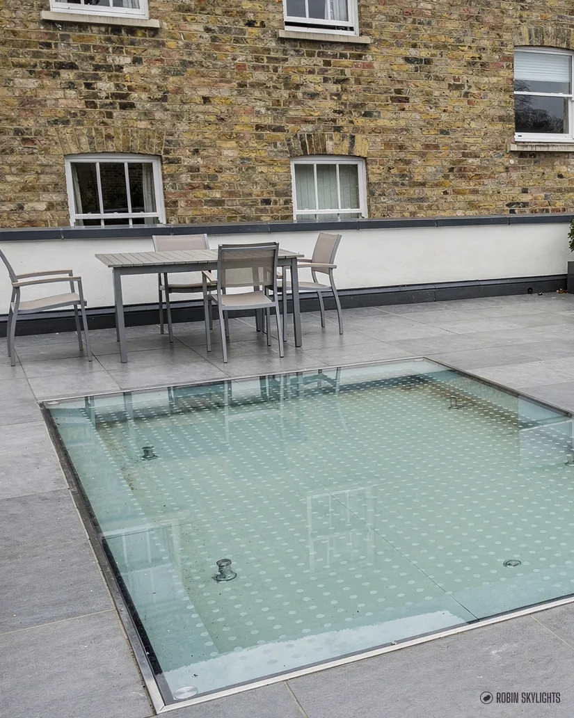 Walk-on rooflight in a paved terrace with a table and chairs