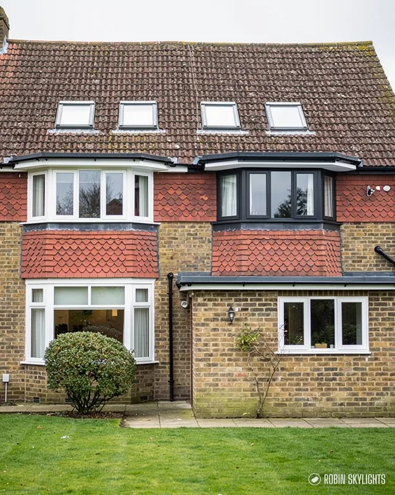 Rear of a brick and render house with roof windows and a lawn