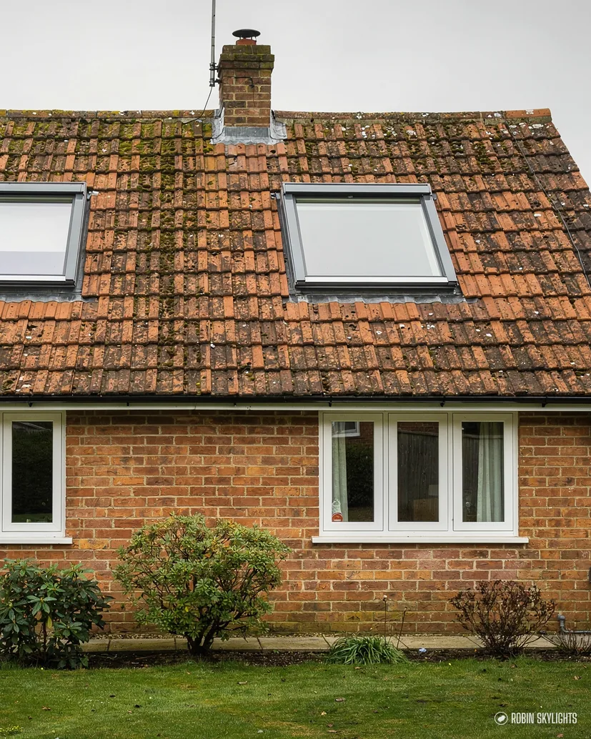 Brick cottage with roof windows in a weathered clay tile roof