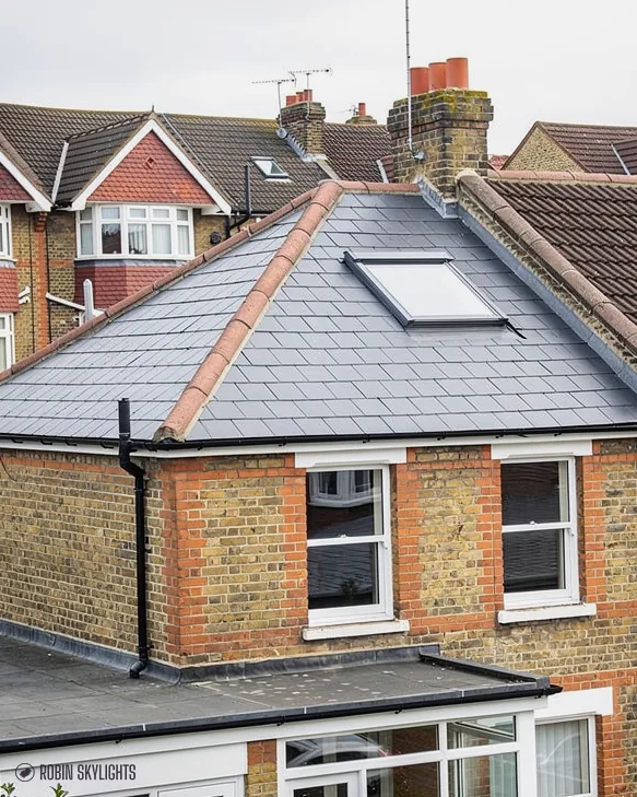 Brick house with roof windows in a hipped slate roof