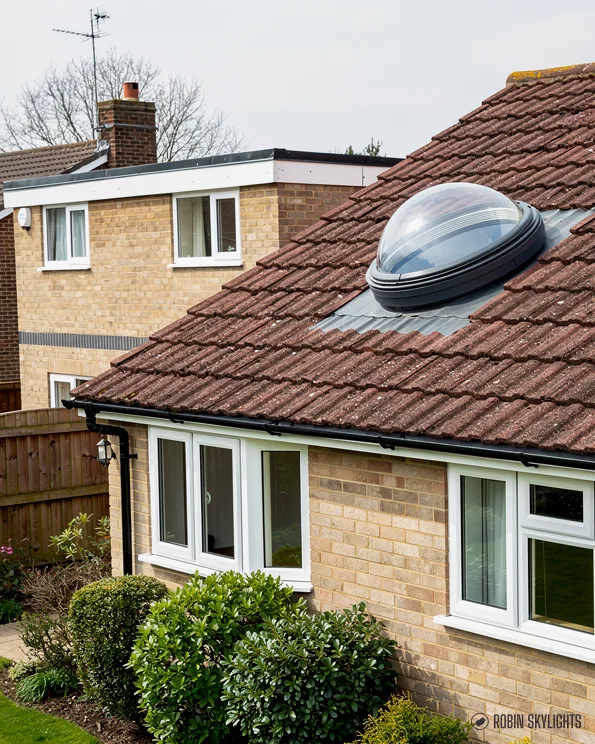 Sun tunnel dome on the tiled roof of a brick bungalow