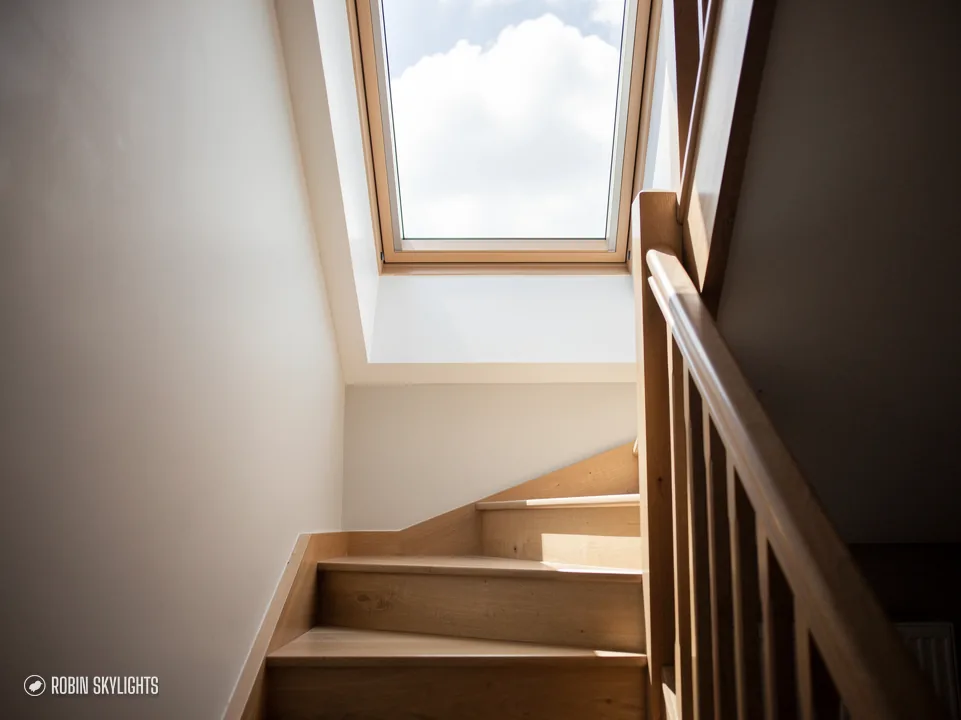 Timber staircase rising to a roof window in a sloping ceiling