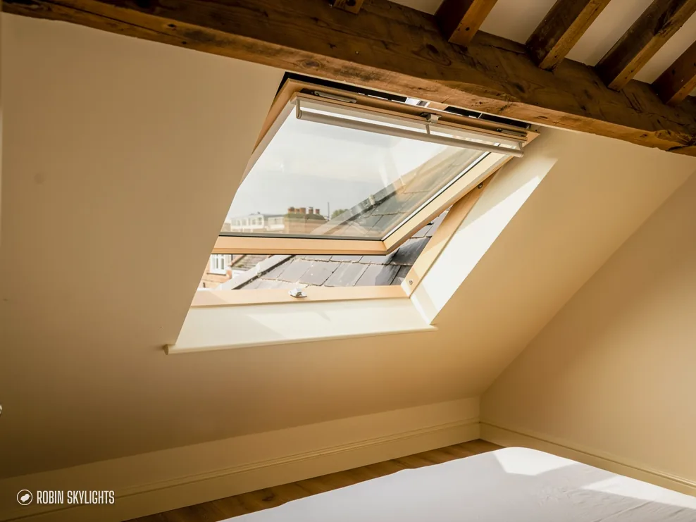 Open roof window in a sloping ceiling with timber beams