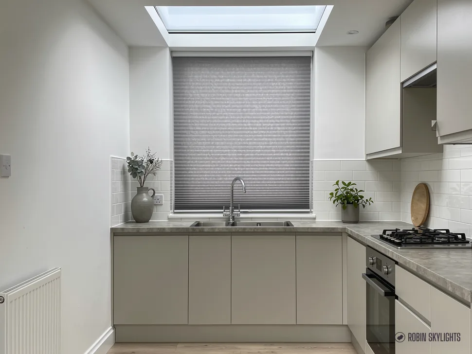Pale kitchen with a sink under a blinded window and flat rooflight