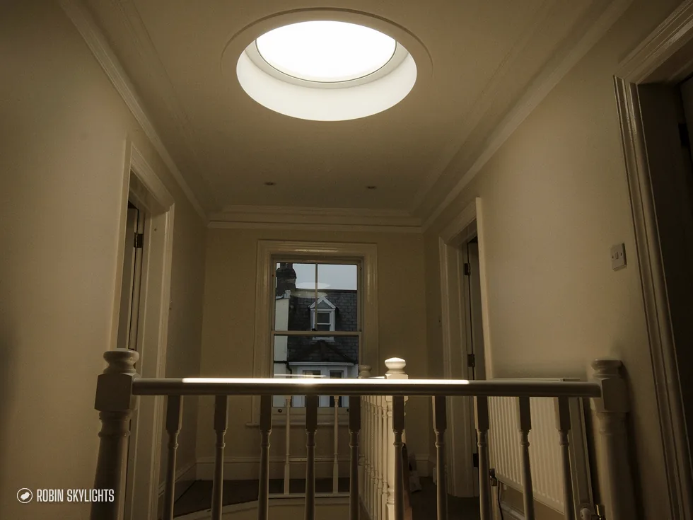 Landing with wooden spindles and a round sun tunnel in the ceiling