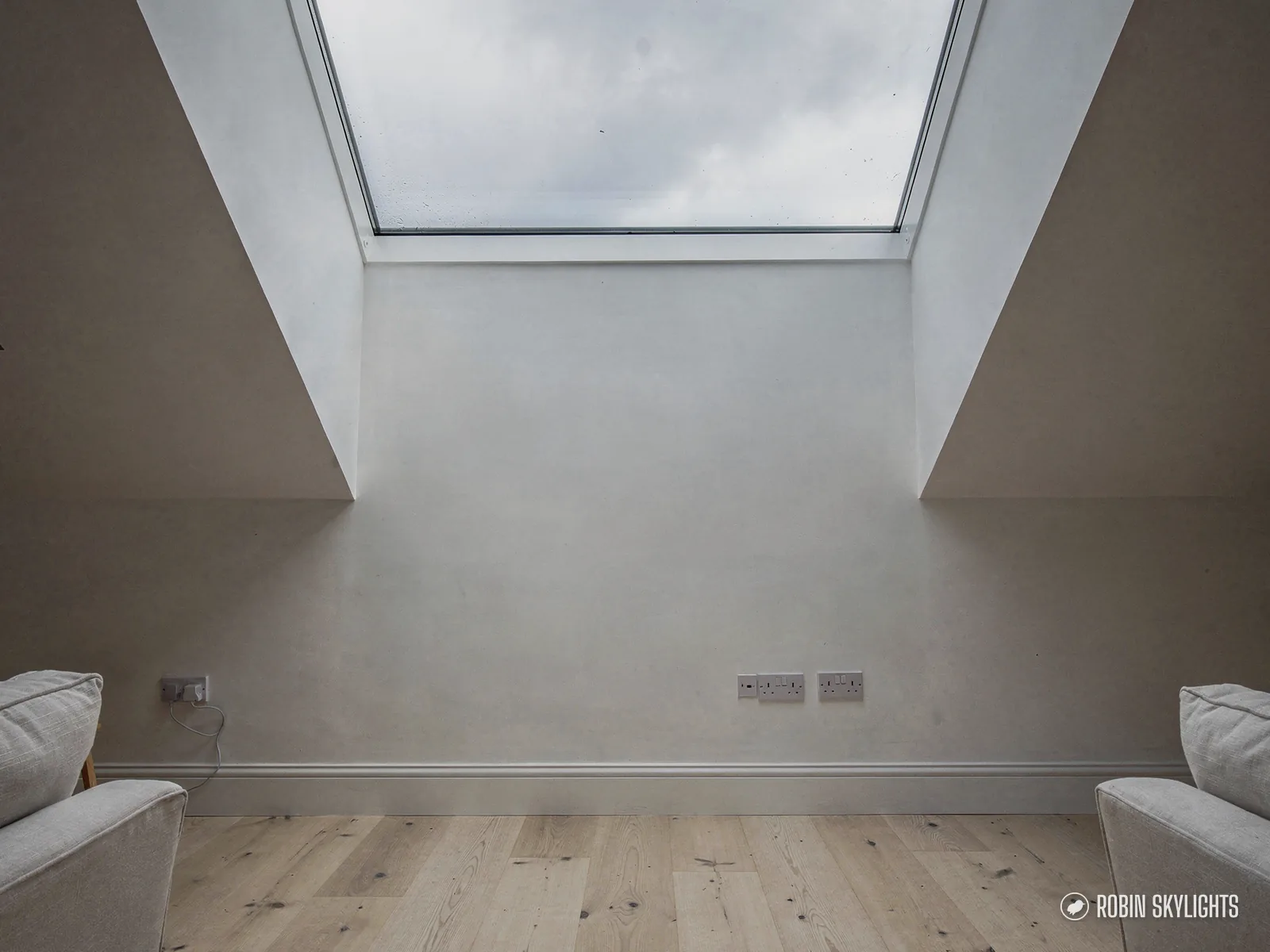 Empty white room with a light oak floor under a roof window