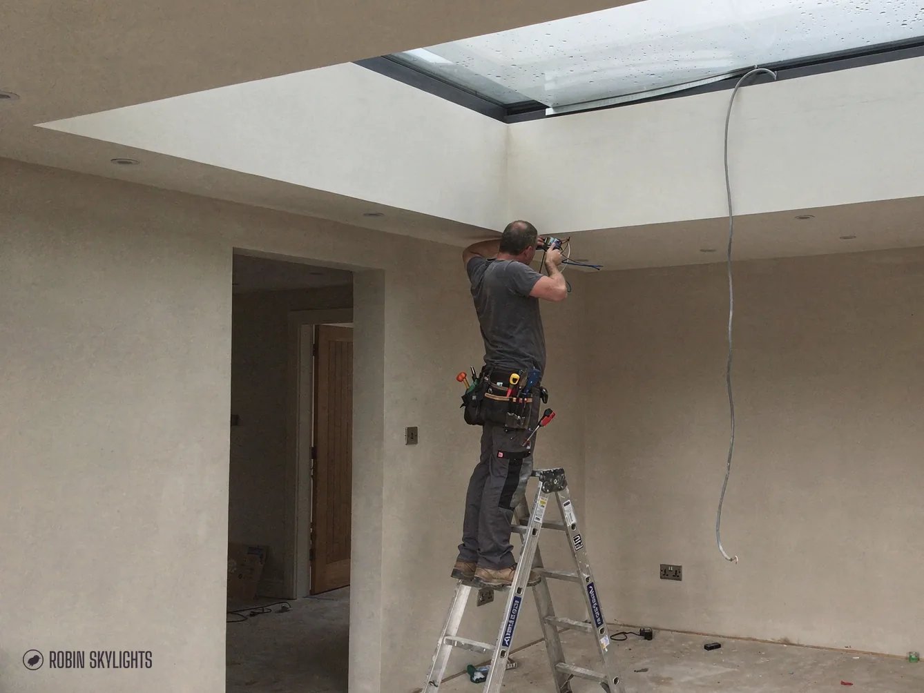 Fitter on a stepladder working beneath a new flat rooflight