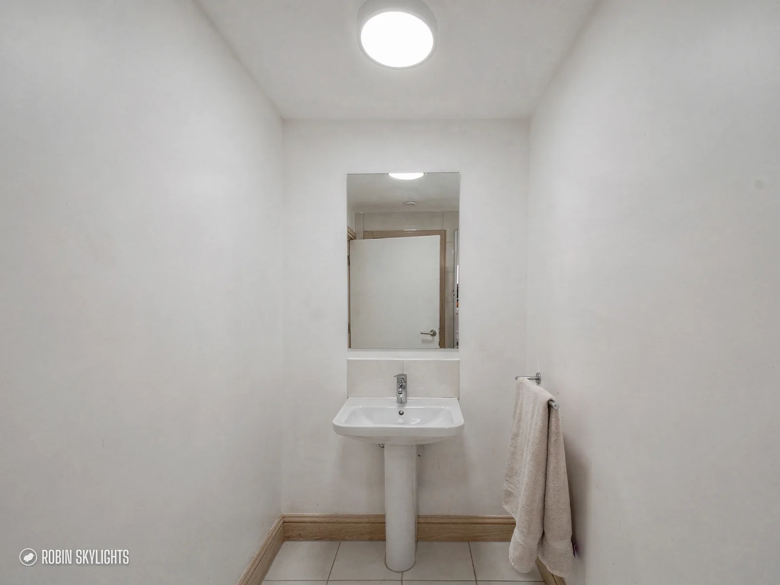 Small white cloakroom with a basin and sun tunnel above