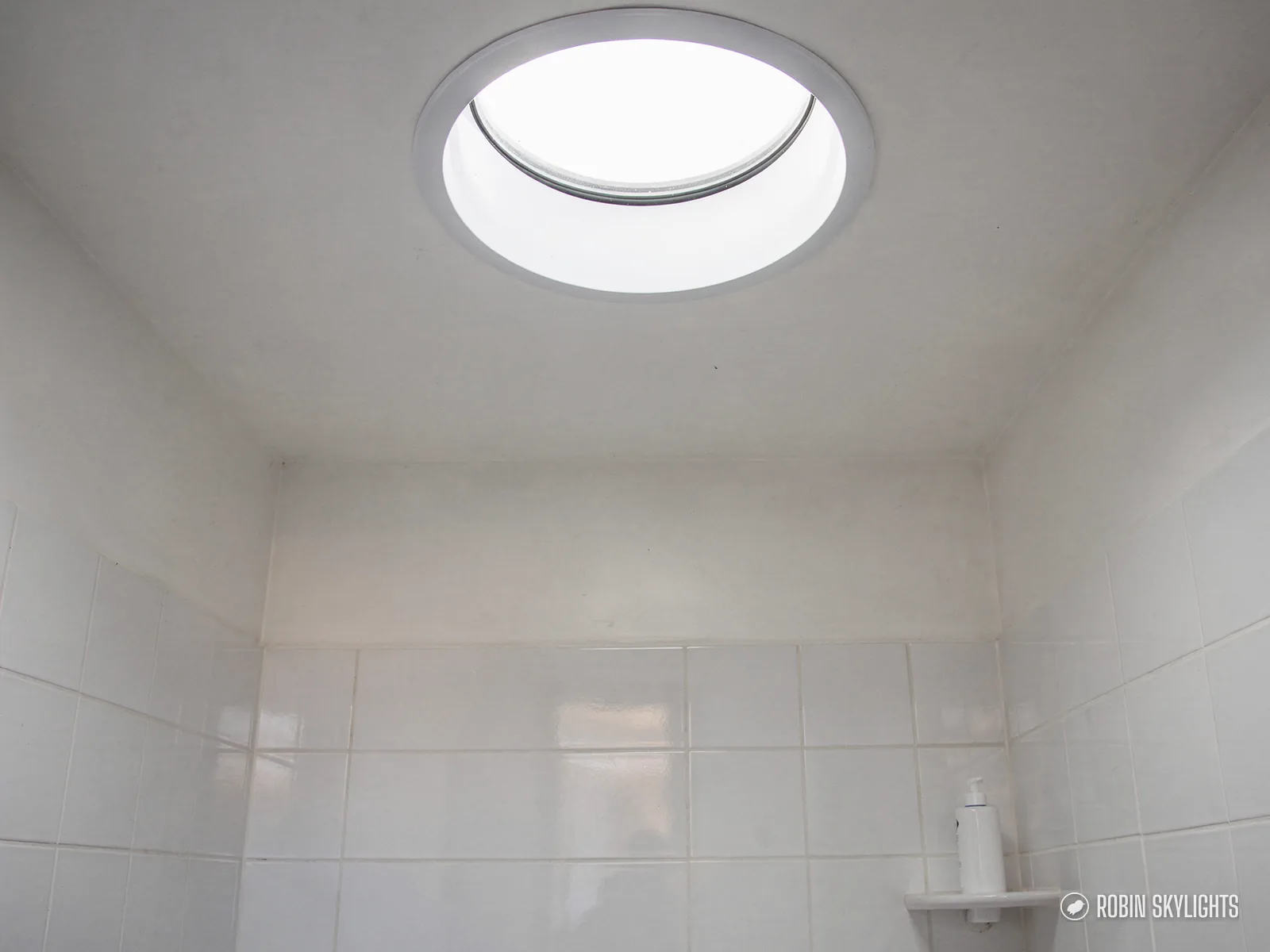 White tiled room with a round sun tunnel diffuser overhead