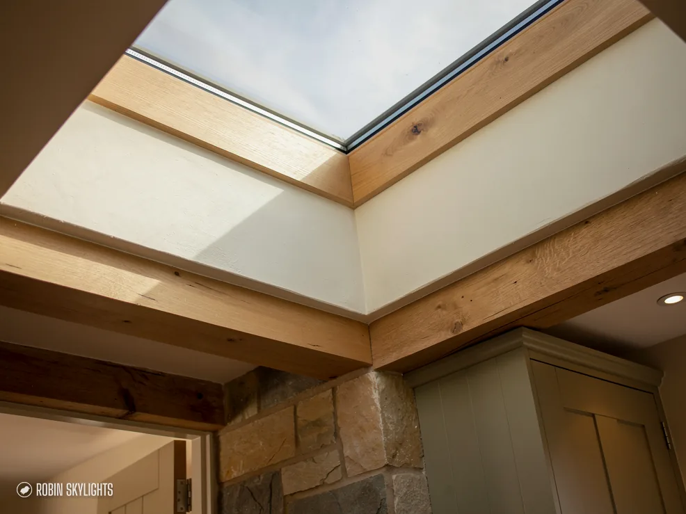 Rooflight framed by pale timber boards in a ceiling