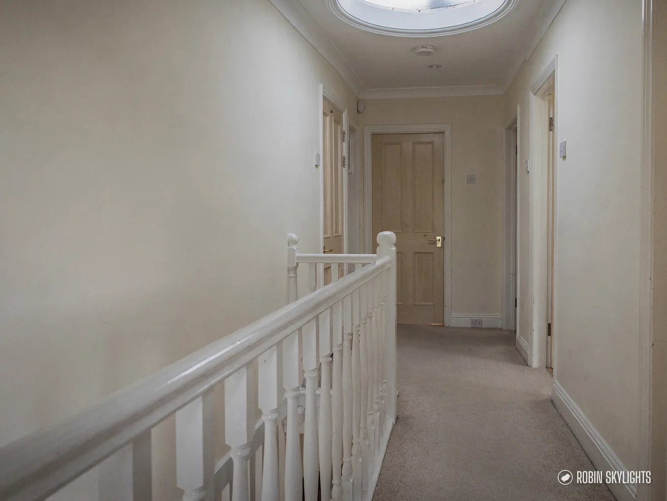 Upstairs landing with white spindles and a sun tunnel overhead
