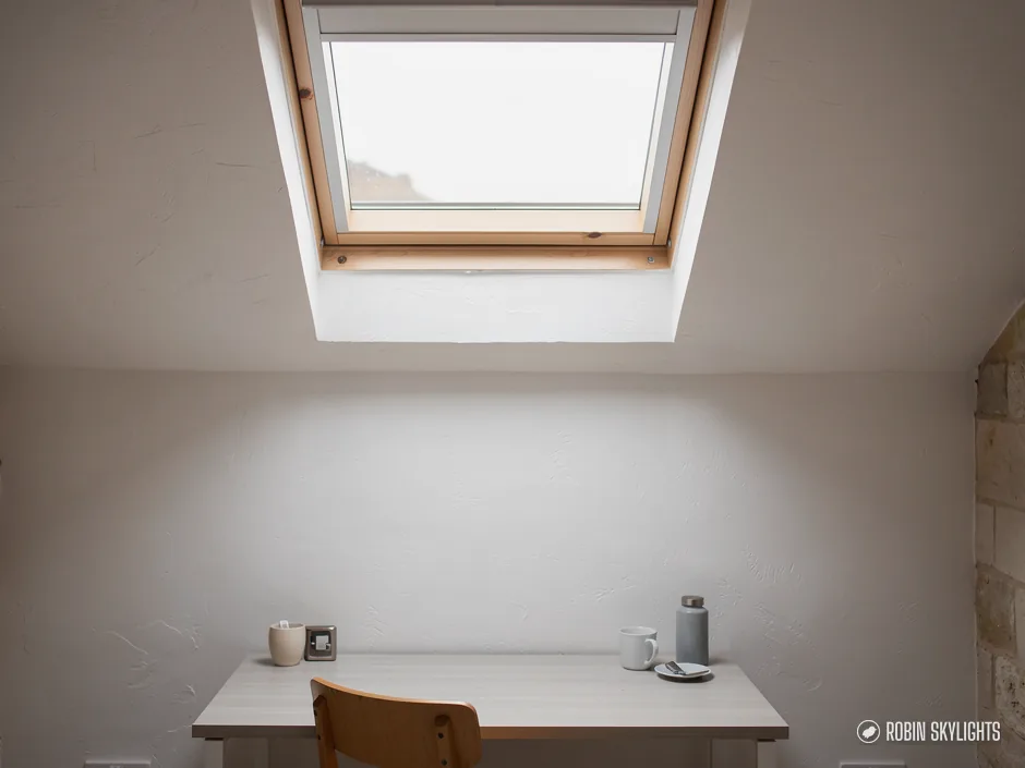 Pine roof window above a small desk in a white room