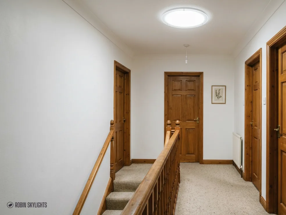 Landing with a wooden door and a round sun tunnel in the ceiling