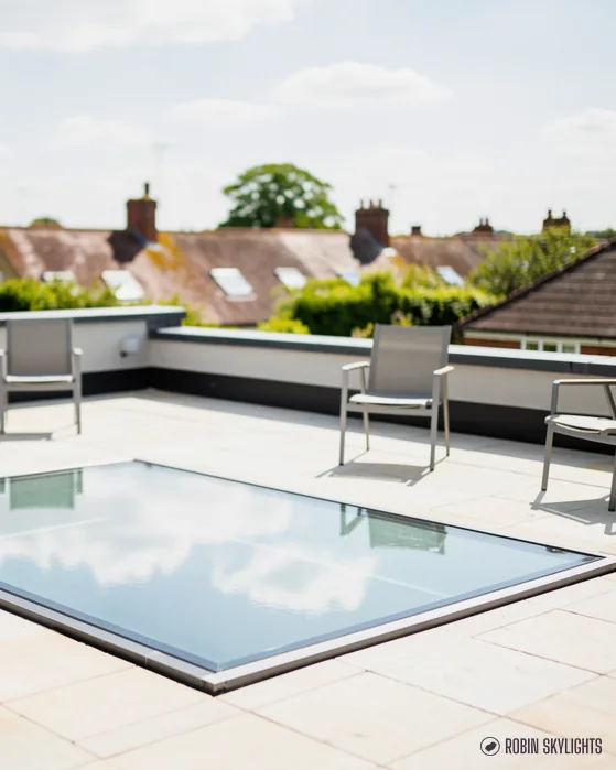 Walk-on glass rooflight in a paved roof terrace with garden chairs