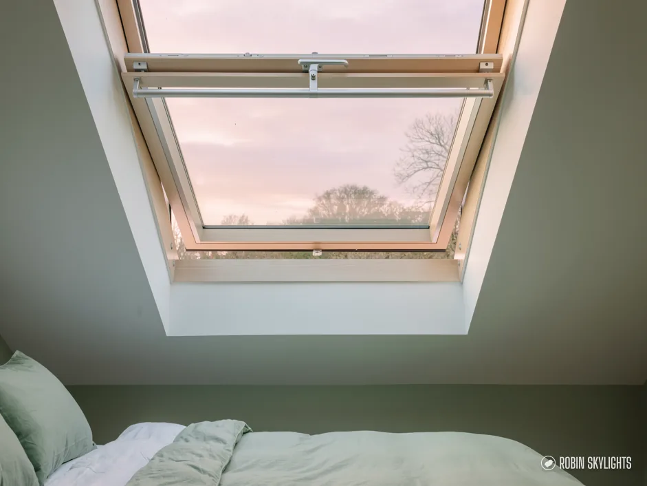 Bedroom with a roof window showing an evening sky