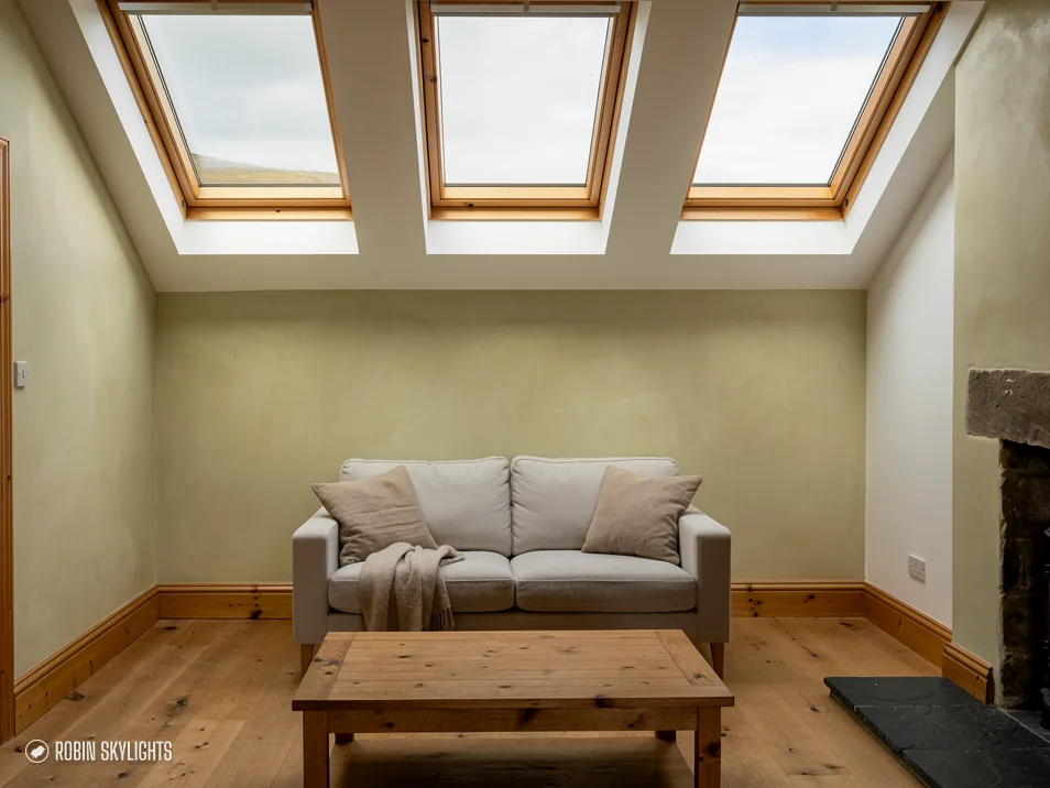 Lounge with a sofa beneath three roof windows in the slope