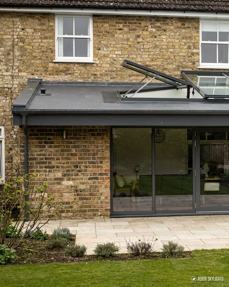 Yellow brick house with a dark roof lantern on its rear extension