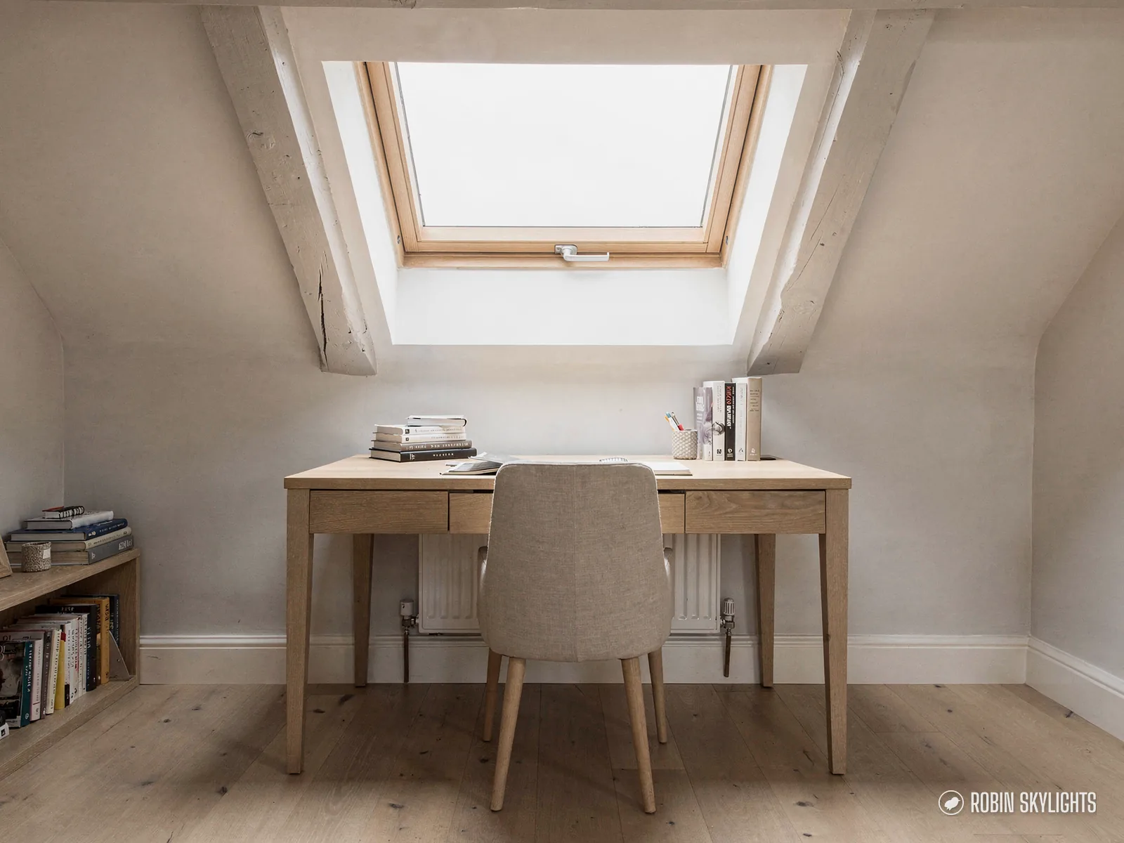 Desk and upholstered chair beneath a roof window