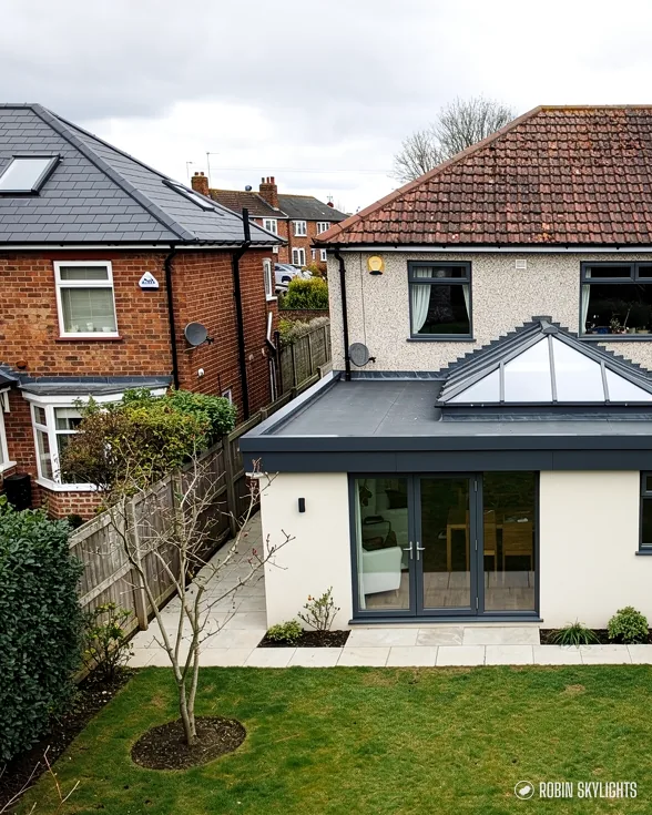 White rendered extension with a roof lantern beside brick houses