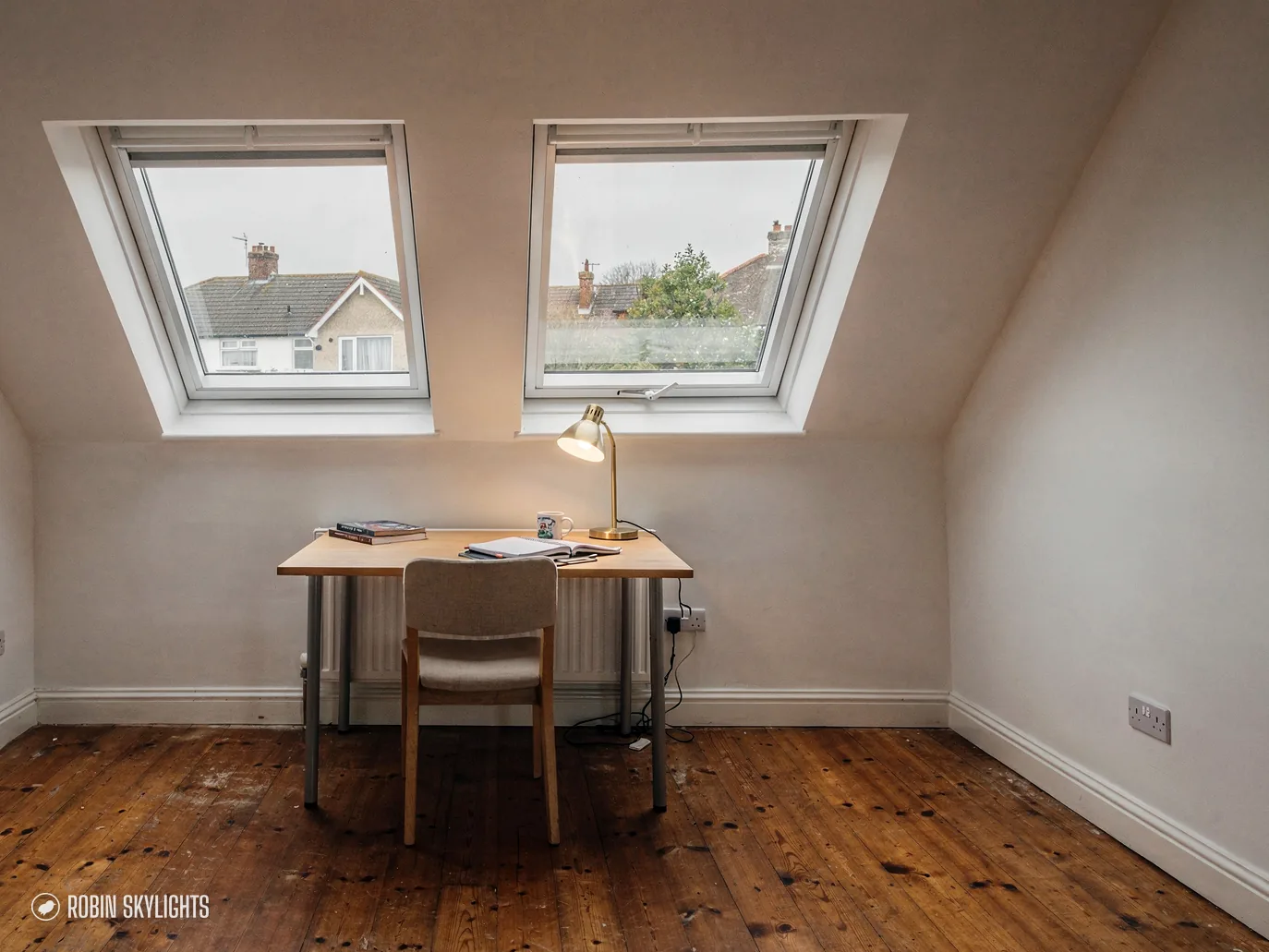 Desk and chair under two roof windows on a wooden floor