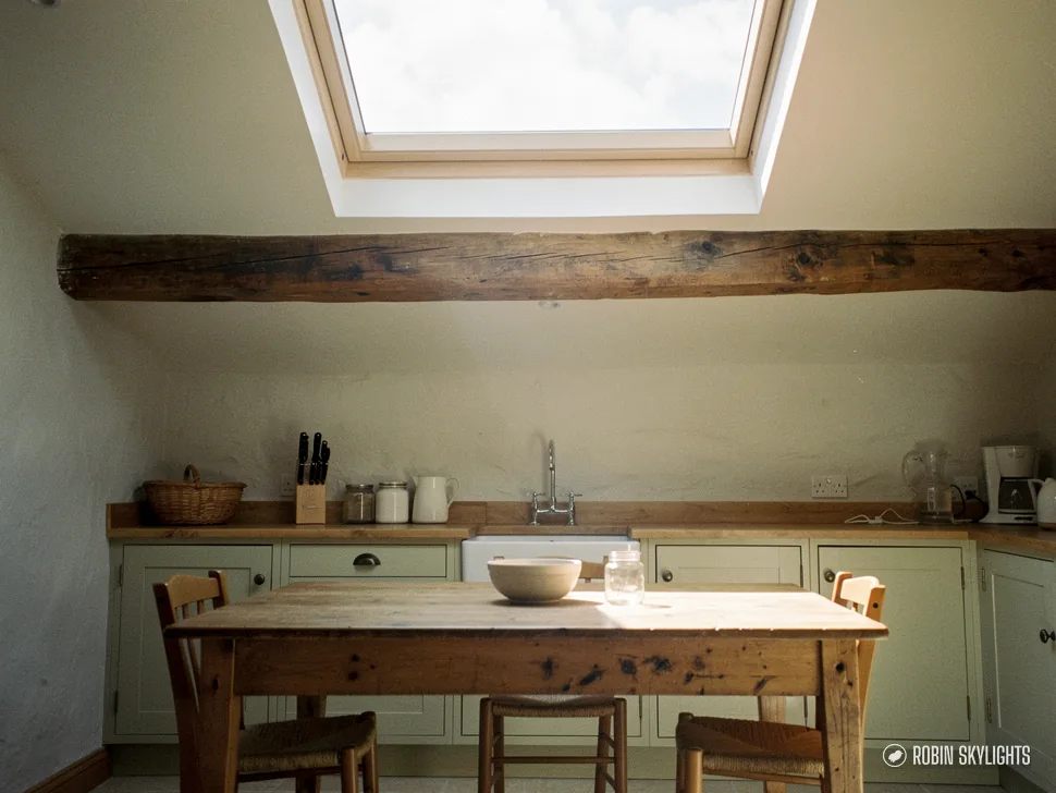 Kitchen with a dark beam and dining table under a rooflight