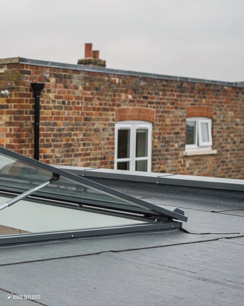 Flat rooflight on a membrane roof beside a brick house
