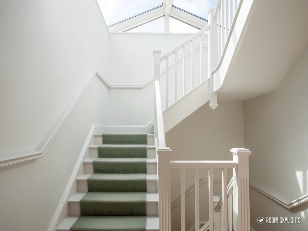 White staircase with green carpet under a roof lantern